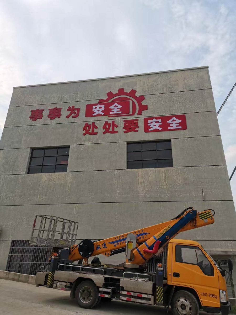 灰白墙面上的安全标语大字,是现场弹线定位后一个字一个字装上去的。