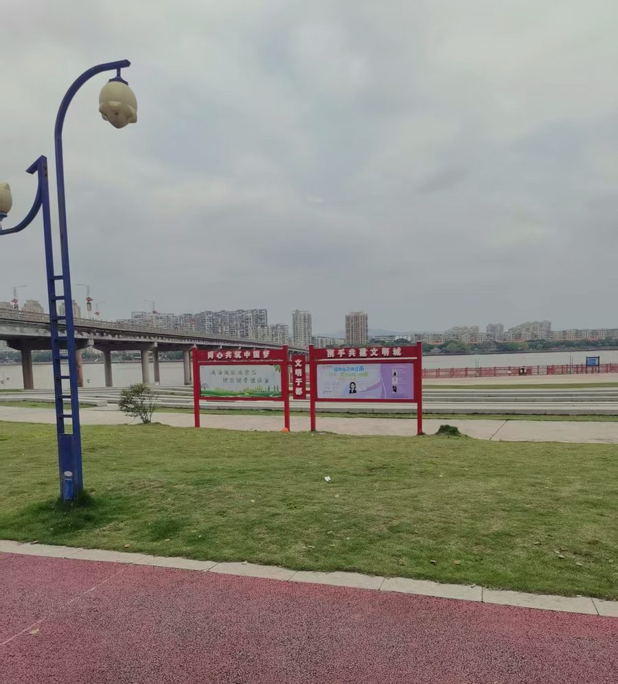 县城河边的户外宣传栏:画面定期更换,墙才一直有人看。