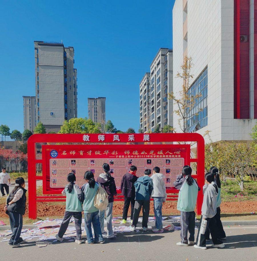 于都一所学校的户外风采栏:框架没动,画面换新,课间学生围着看。