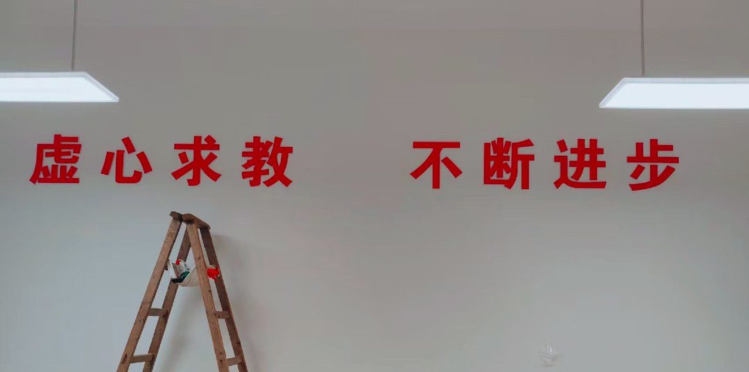教室里的标语墙刚贴完字，梯子还在现场——校园墙一年要动好几回，做死不划算。